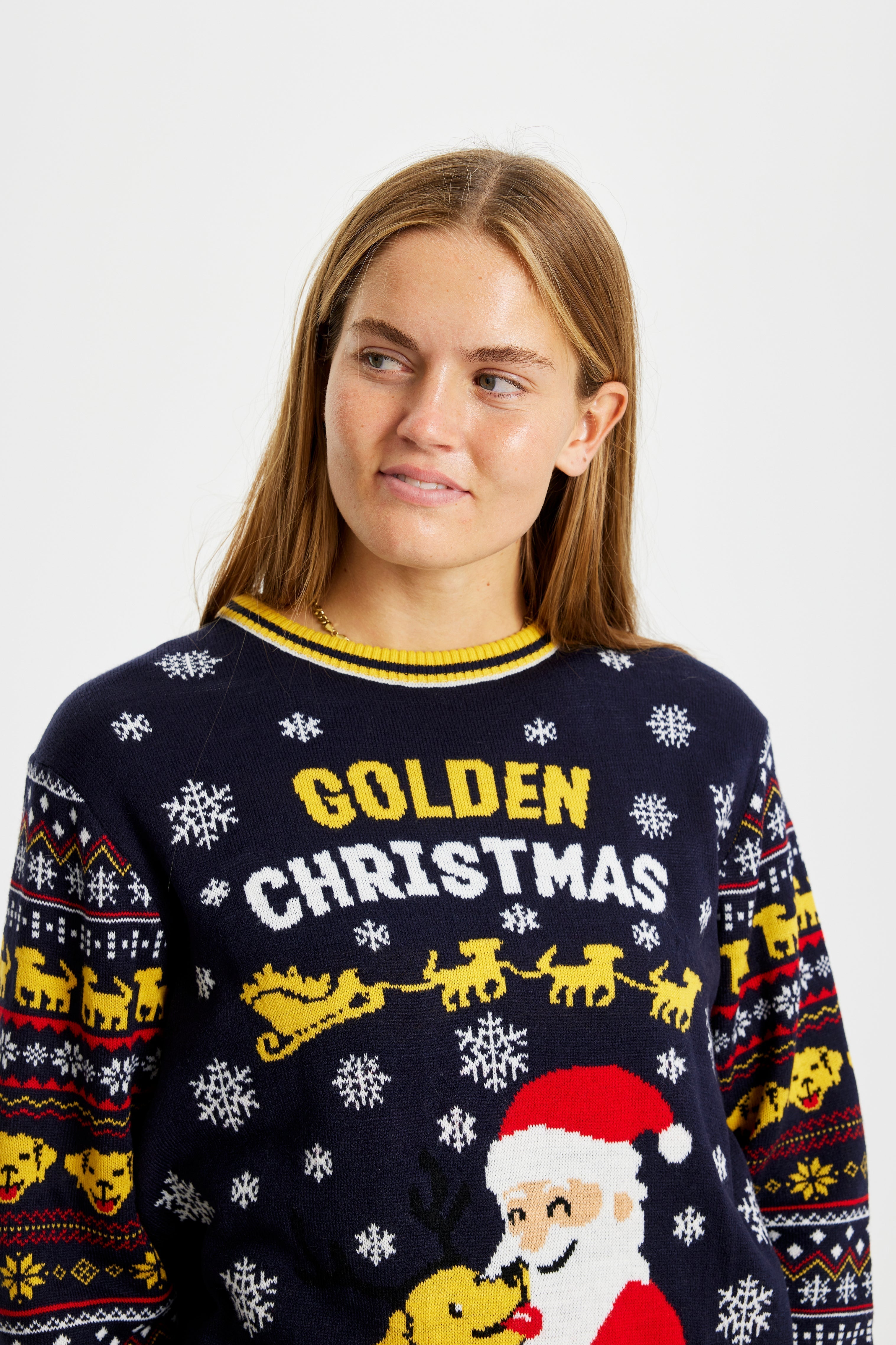 Una simpatica donna che indossa un maglione natalizio giallo e blu con un Babbo Natale e un cane.